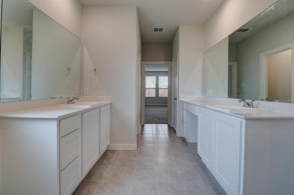 Dual vanity with integrated sinks, white cabinetry, expansive mirrors, tiled flooring, and recessed lighting
