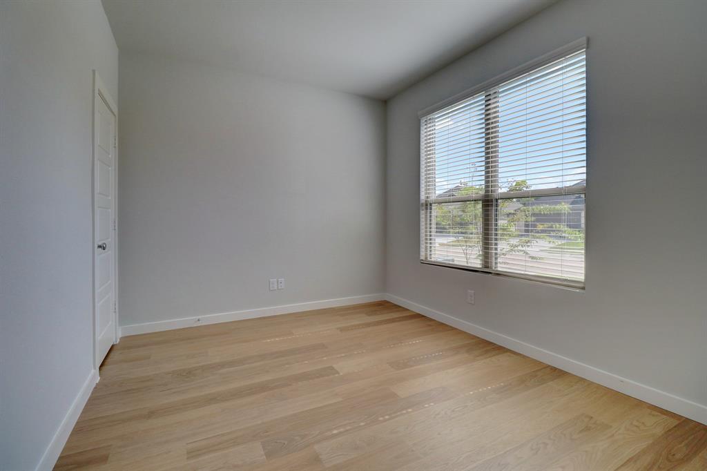 Light wood-finish flooring, white walls, double French doors with frosted glass, and a large window with blinds
