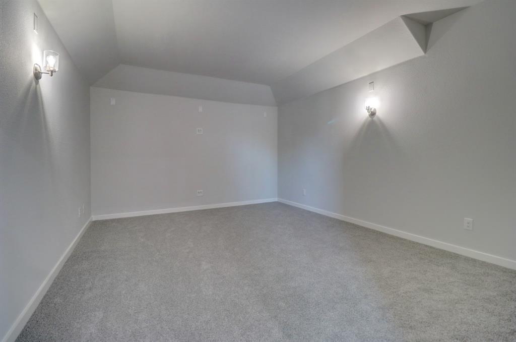 Vaulted ceiling with sconce lighting and neutral-toned carpet