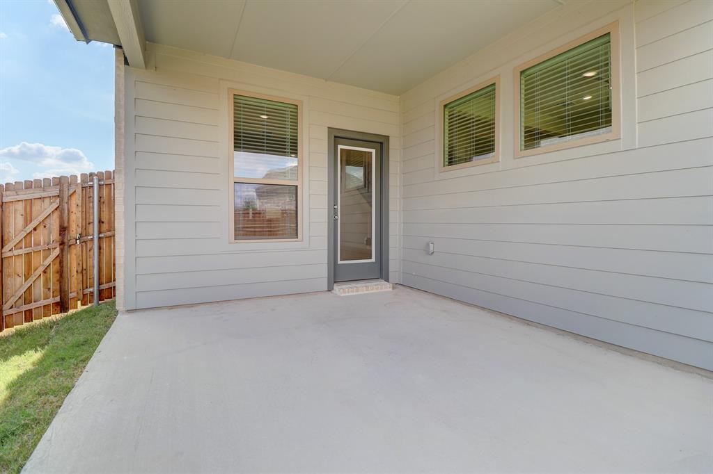 Covered concrete patio with siding exterior, wood fence, and glass-paneled door