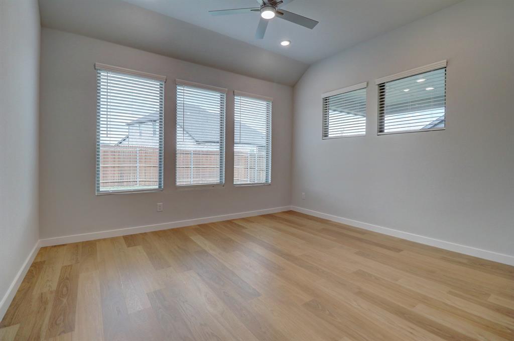Varnished wood-finish flooring, vaulted ceiling, recessed lighting, and multiple windows with blinds