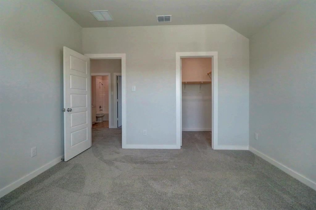 Wall-to-wall carpeting with light gray walls, an open closet with built-in shelving, and a five-panel interior door