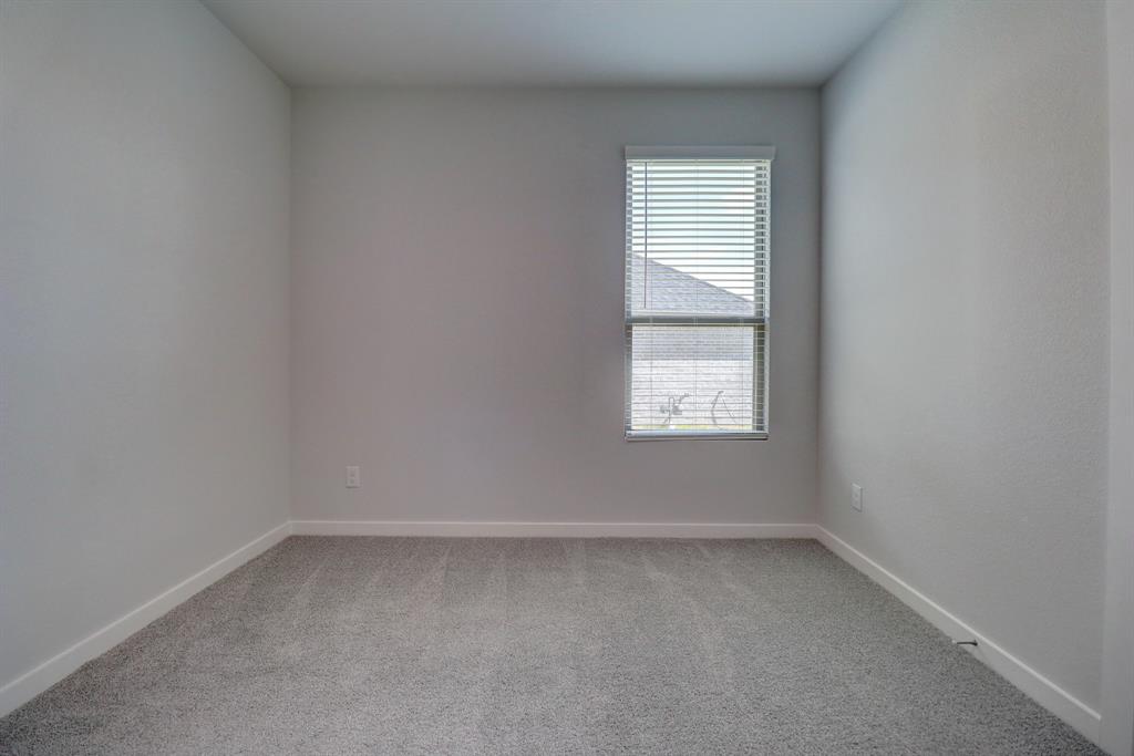 Light grey textured carpeting, white baseboards, and a window with horizontal blinds
