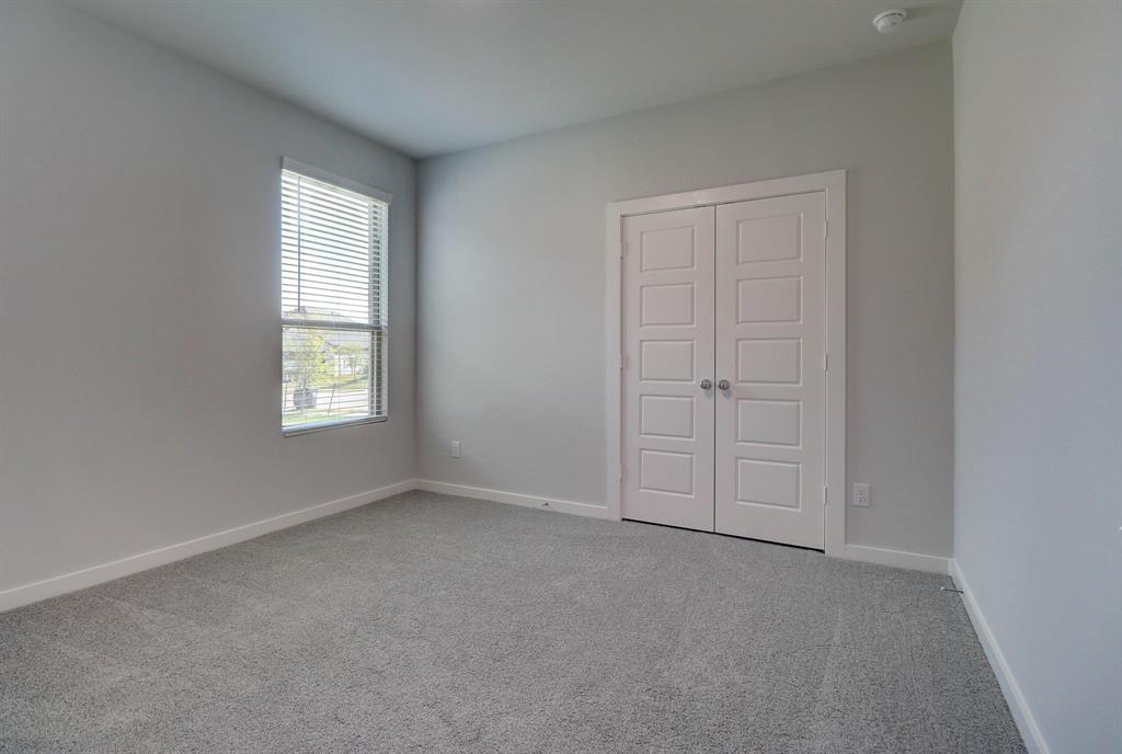 Neutral wall color, gray carpeting, rectangular window with blinds, and white paneled double doors