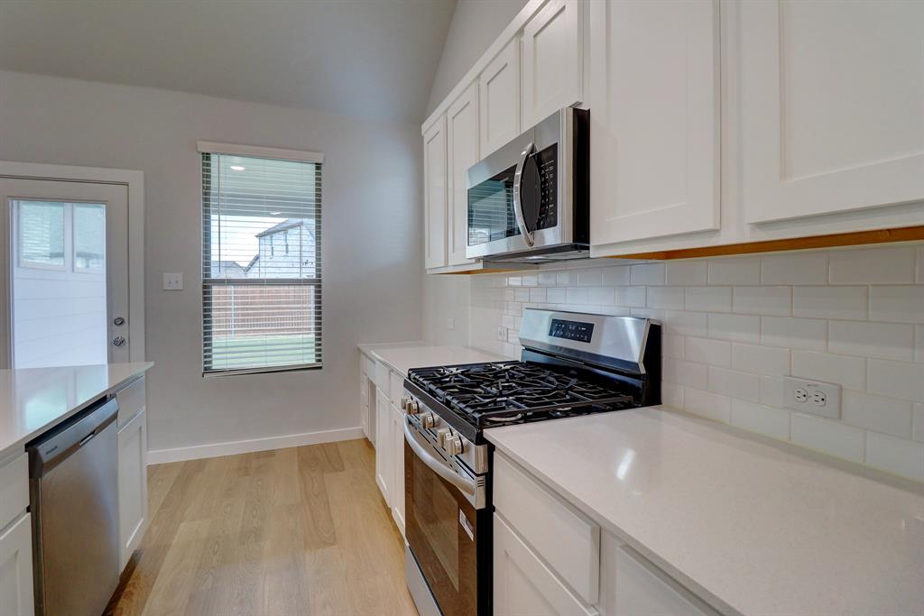 White shaker-style cabinetry, wood-finish flooring, stainless steel appliances, white subway tile backsplash, and light-colored countertops