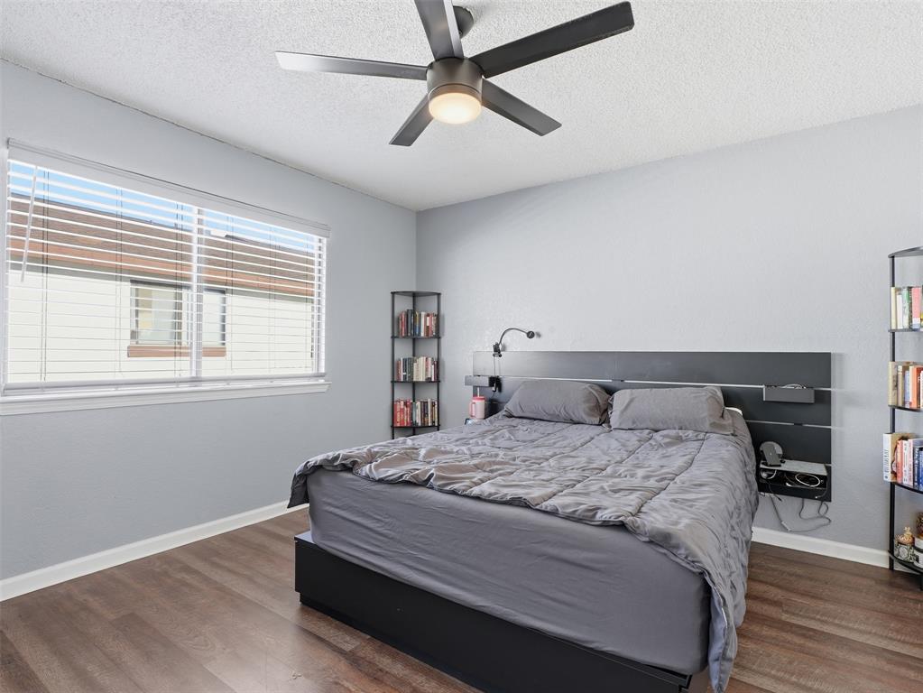 Wood-finish flooring, matte black ceiling fan with integrated lighting, and horizontal window blinds
