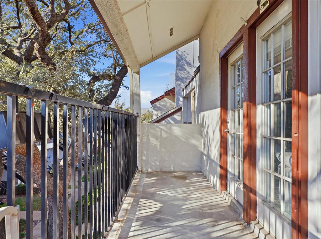 Covered balcony featuring concrete flooring, black metal railing, and dual glass-paneled exterior doors with wood-finish trim