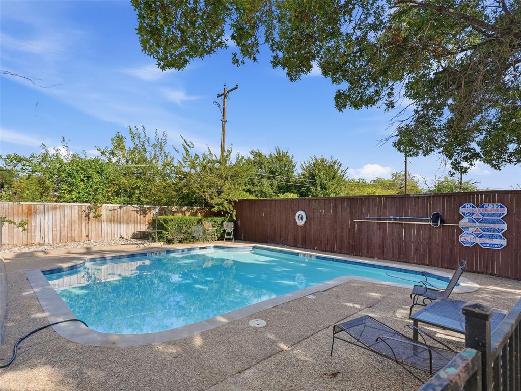 In-ground swimming pool featuring a textured aggregate deck and wood privacy fencing