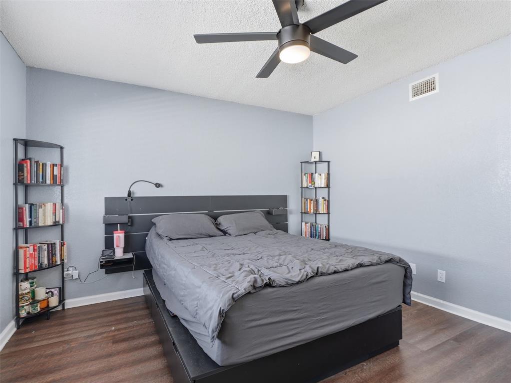 Wood-finish flooring, dark-finish ceiling fan with integrated lighting, and neutral-toned wall paint