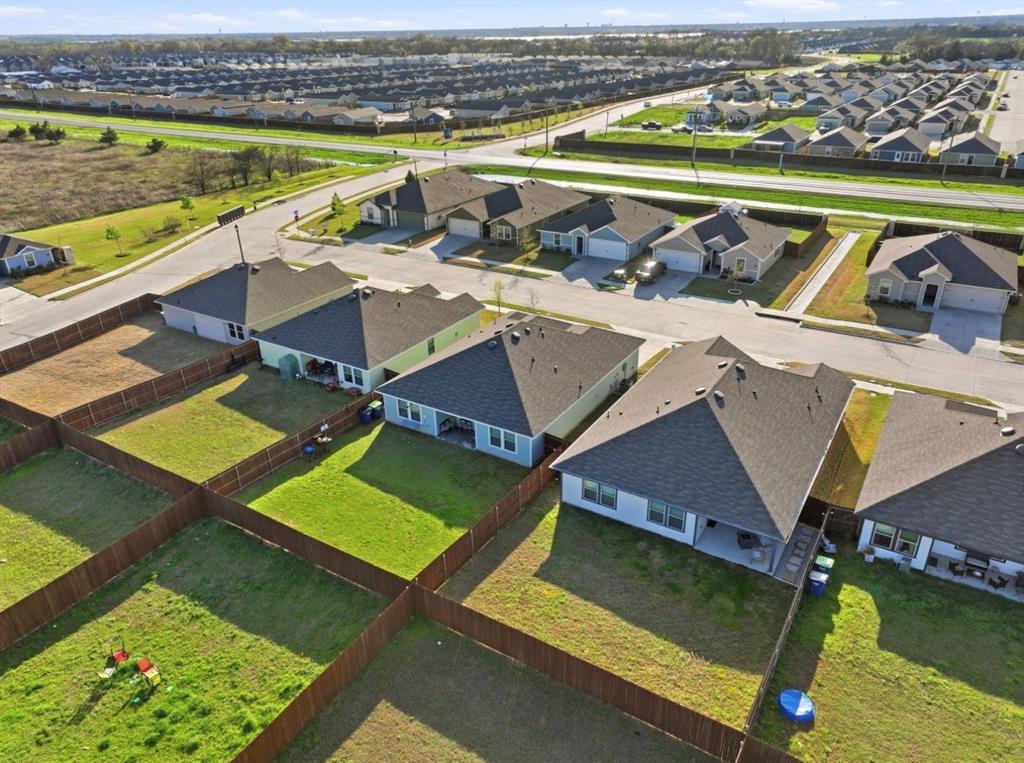 Aerial perspective of a residential property featuring a fenced backyard, a rear covered patio, and a shingle roof