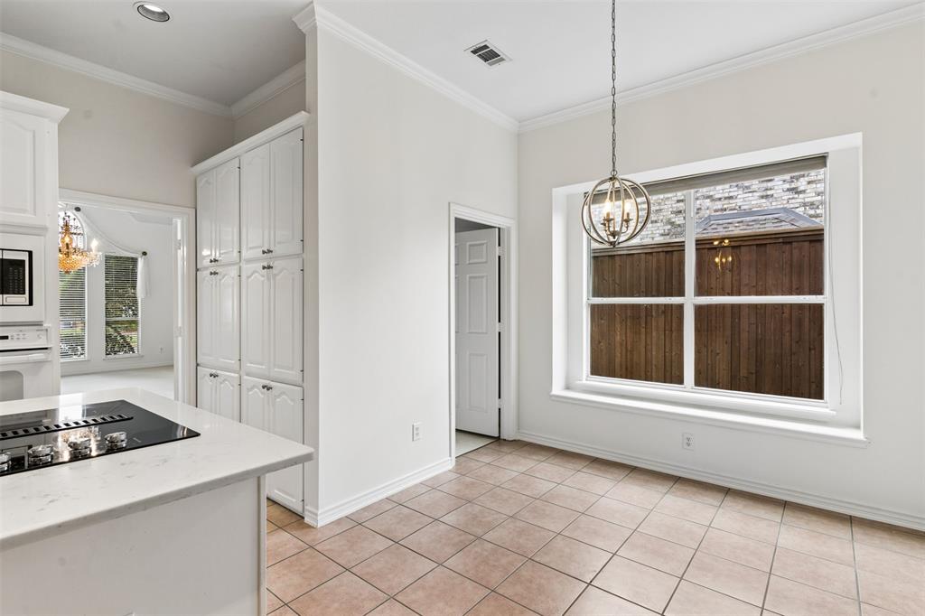 Kitchen area featuring tile flooring, white cabinetry, a stone-finish countertop with an integrated stovetop, and a suspended orb chandelier