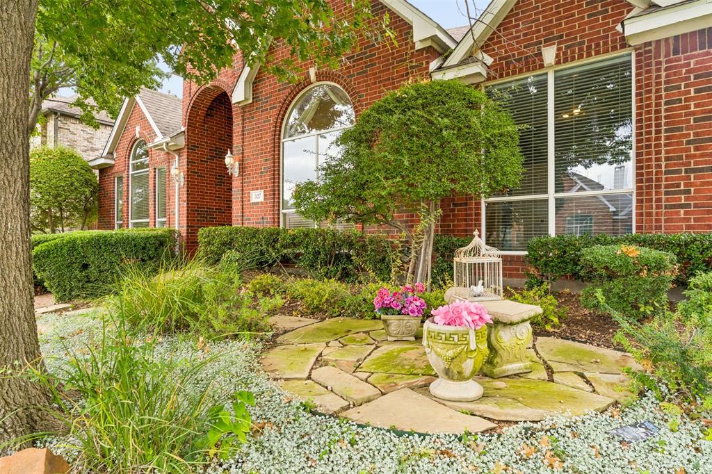Brick exterior featuring an arched entryway, stone patio hardscaping, and large multi-pane windows