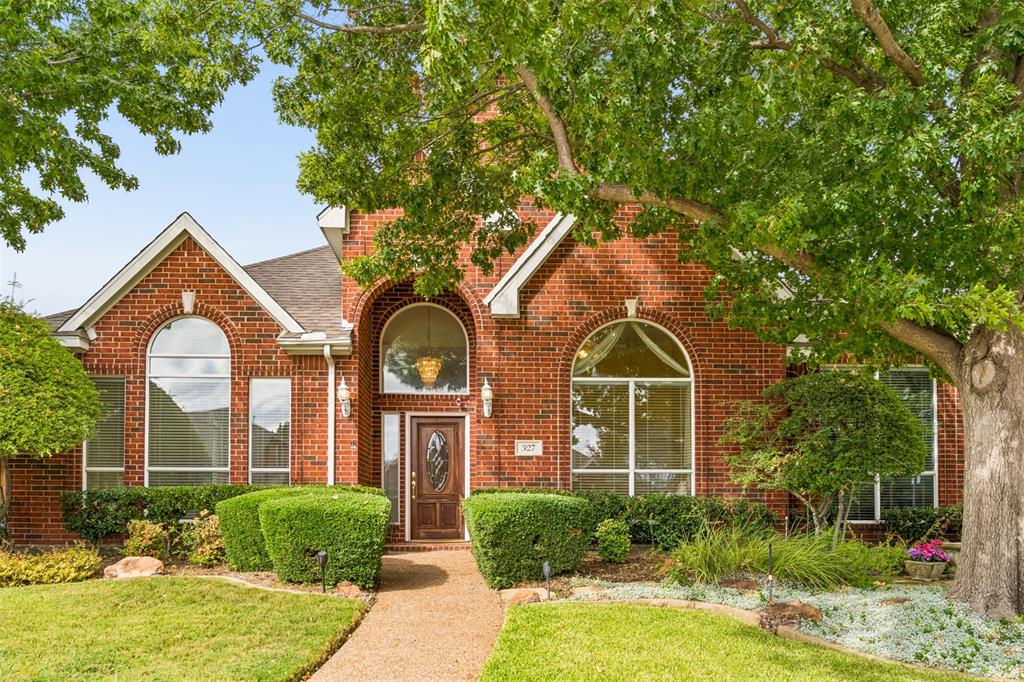 Brick exterior featuring a recessed entry, arched windows, and mature landscaping