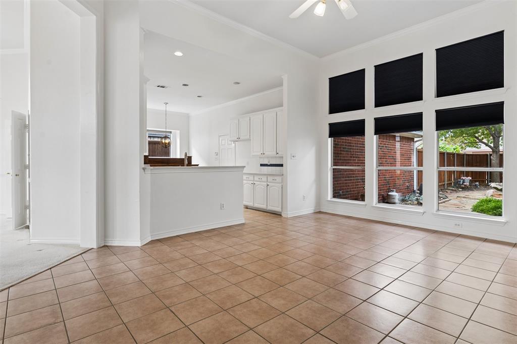Open-concept room featuring tile flooring, high ceilings, large windows with black shades, and built-in cabinetry