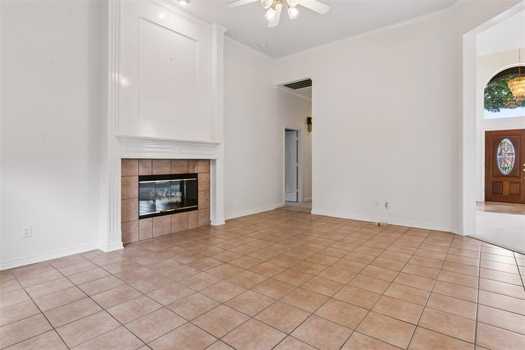 family room area featuring tile flooring, high ceilings with a central fan, and a floor-to-ceiling fireplace mantel with tile surround