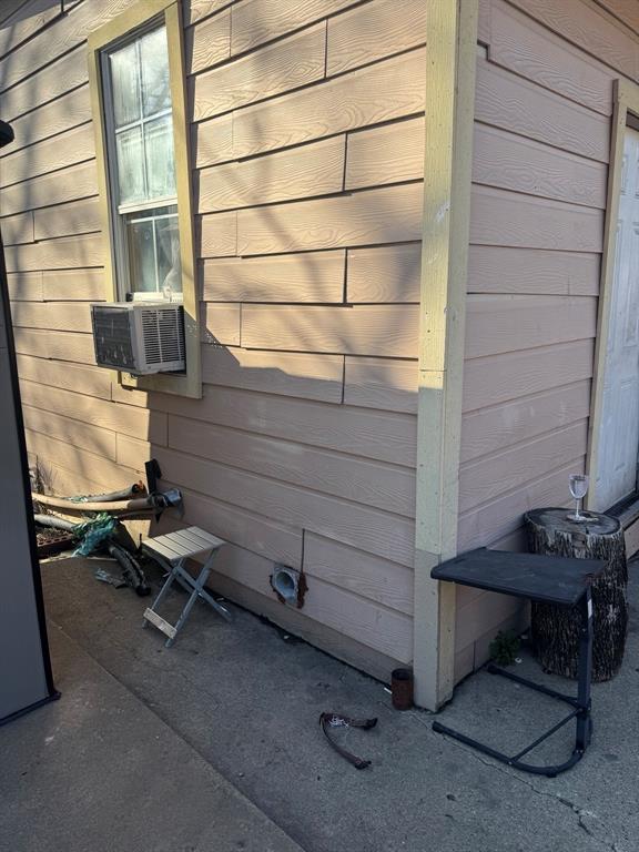 Side exterior featuring horizontal siding, concrete walkway, and an exterior access door.