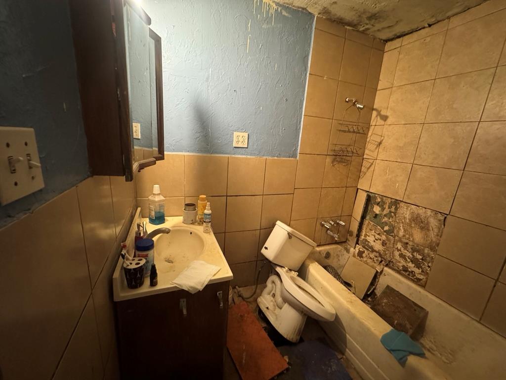 Bathroom featuring a single-sink vanity and tiled tub/shower combination.