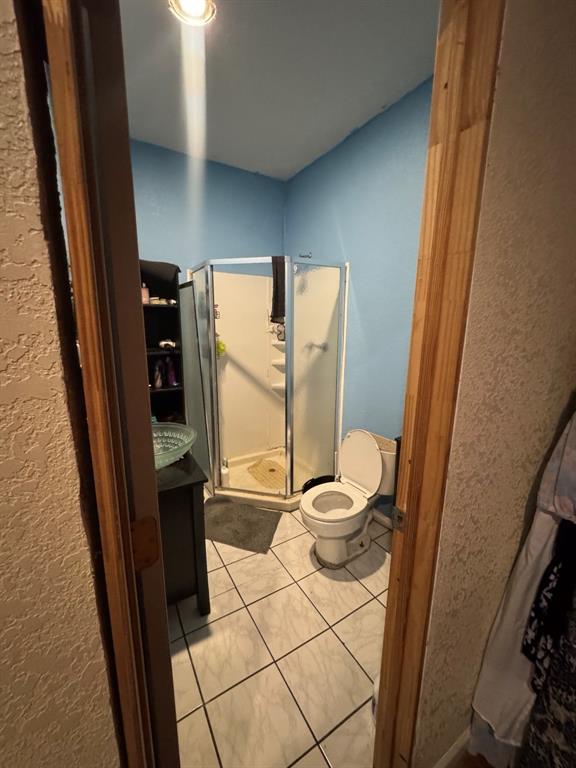 Tile flooring, glass-enclosed shower, built-in vanity with vessel sink, and recessed lighting.
