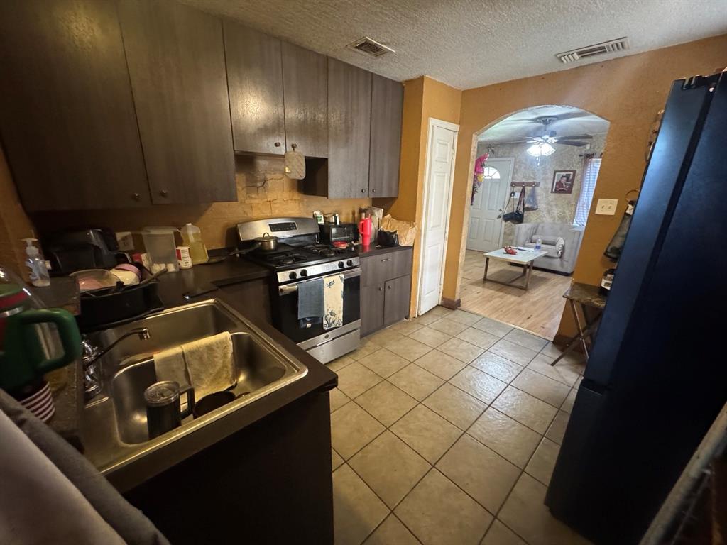 Additional kitchen view showcasing cabinet storage, countertop space, tile flooring, and arched opening to the living area.