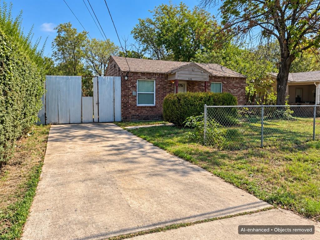 Single-story brick home featuring a concrete driveway, fenced front yard, and gated side access.