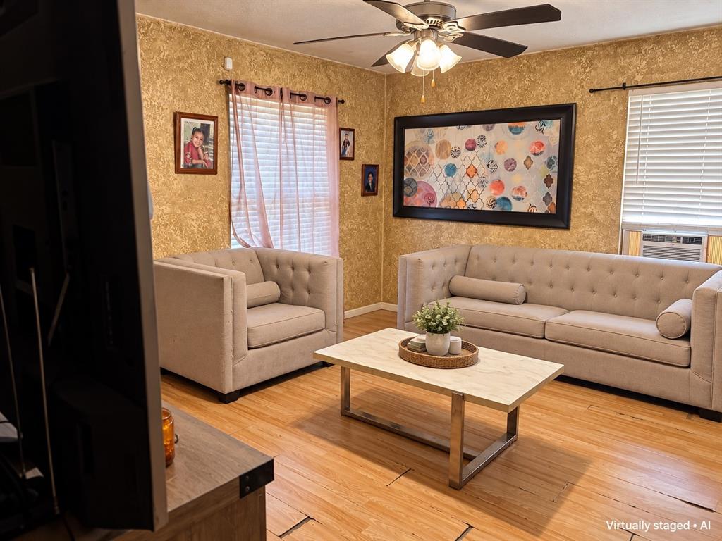 Living area featuring wood-look flooring, ceiling fan, and natural light. Virtually staged to showcase furniture placement possibilities.