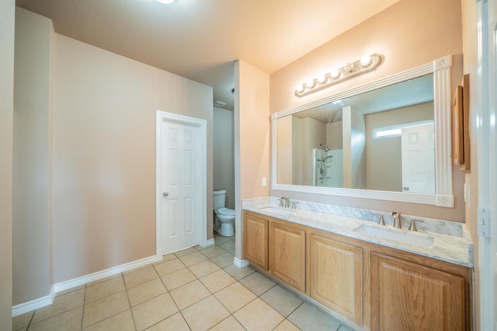 Master bathroom with dual sinks, granite countertop, decorative mirror frame and medicine cabinet.