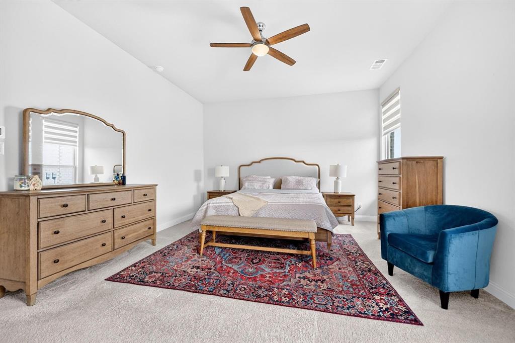 High-ceiling room featuring a central ceiling fan with integrated lighting, neutral wall-to-wall carpeting, and windows fitted with roller shades
