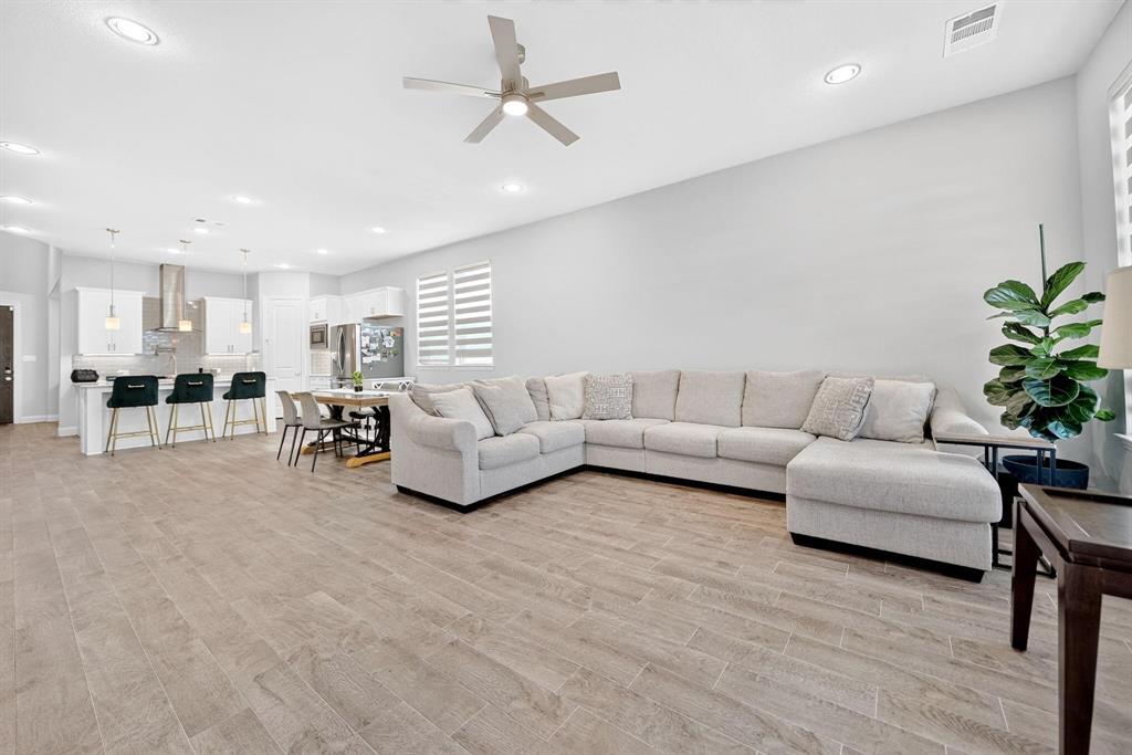 Open-concept interior featuring wood-finish flooring, recessed lighting, a modern ceiling fan, and a kitchen island with pendant lighting