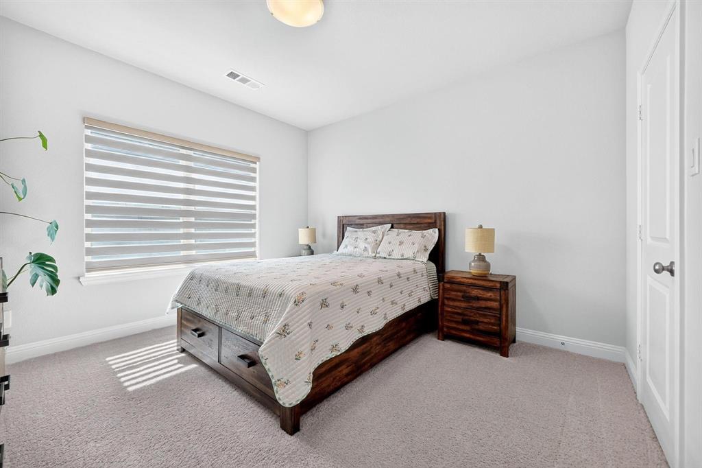 Neutral-toned carpeting, multi-panel interior door, ceiling-mounted light fixture, and window with adjustable roller shades