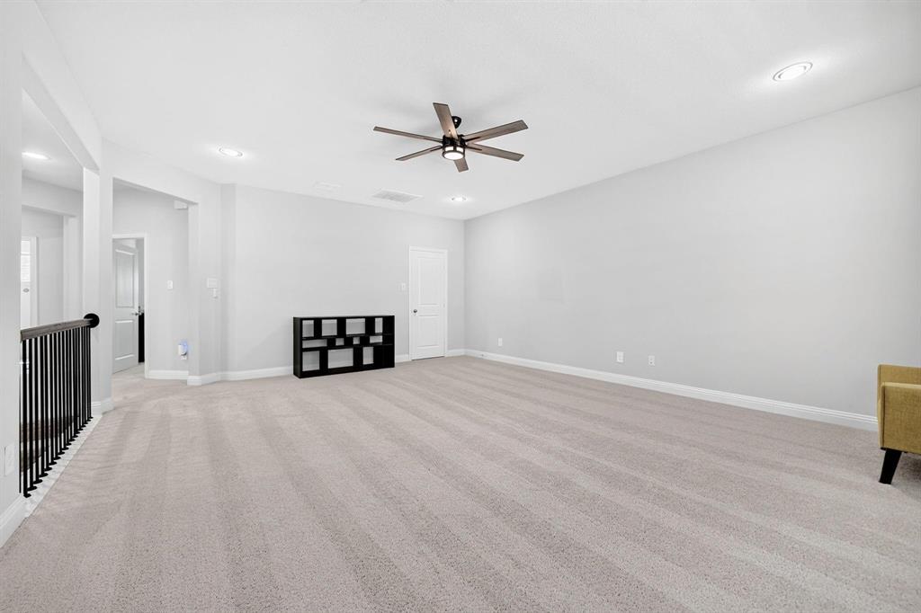 Neutral wall-to-wall carpeting, recessed lighting, ceiling fan with integrated light, and metal spindle stair railing
