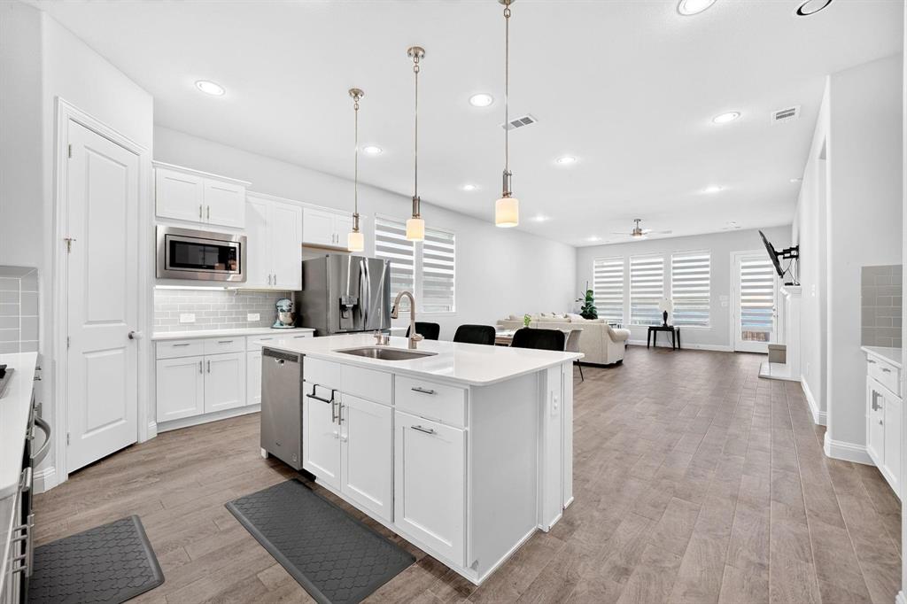 Kitchen featuring white cabinetry, center island with stone-surface countertop, stainless steel appliances, recessed lighting, and wood-finish flooring