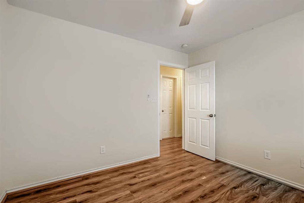 Interior space featuring wood-finish flooring, neutral wall paint, and a six-panel interior door