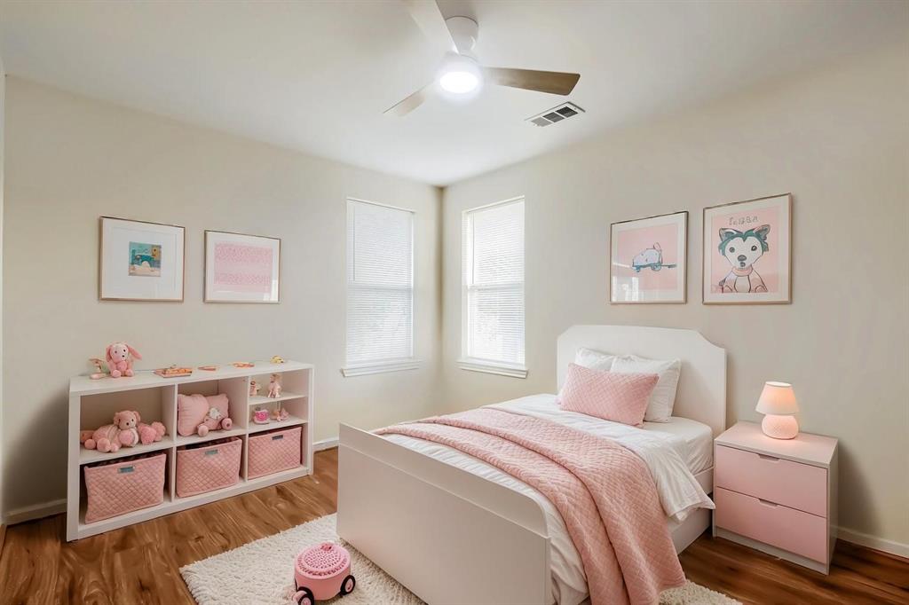 Virtually Staged Bedroom interior featuring neutral-toned walls, laminate wood-finish flooring, dual windows, and an overhead ceiling fan with integrated lighting Virtually Staged Bedroom interior featuring neutral-toned walls, laminate wood-finish flooring, dual windows, and an overhead ceiling fan with integrated lighting