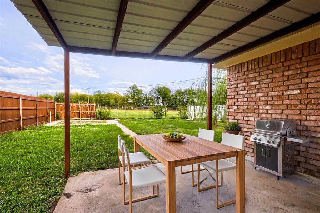Covered patio featuring a concrete slab, exposed brick exterior wall, and metal roof structure overlooking a fenced backyard Covered patio featuring a concrete slab, exposed brick exterior wall, and metal roof structure overlooking a fenced backyard