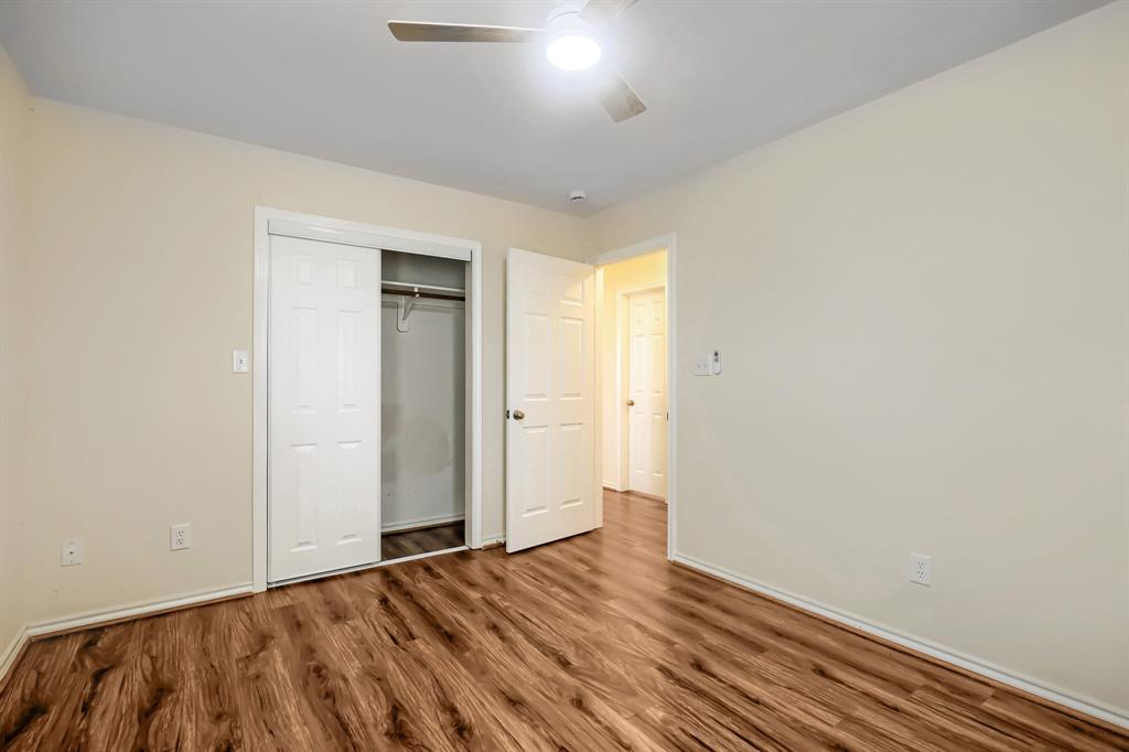 Wood-finish flooring, ceiling fan with integrated light fixture, and closet with sliding paneled doors