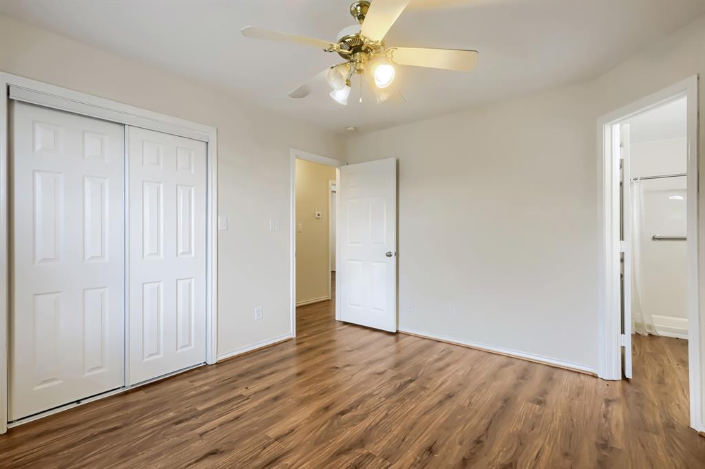 Room featuring wood-finish flooring, a ceiling fan with integrated lighting, and a sliding-door closet