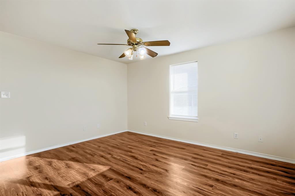 Room featuring laminate wood-finish flooring, a single window, and a ceiling-mounted light fixture with a fan