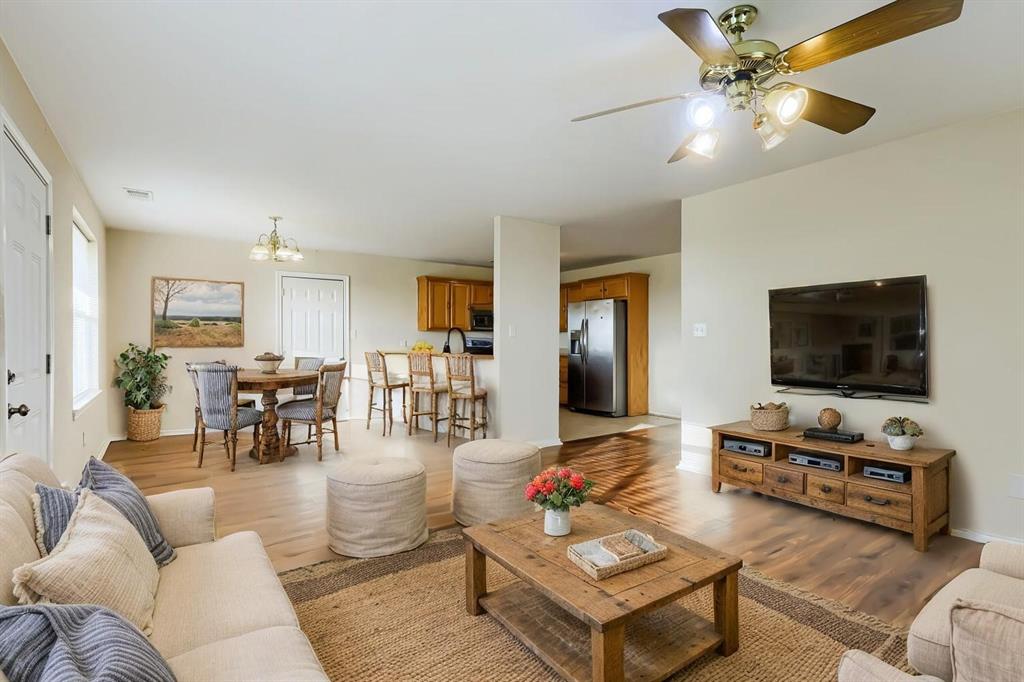 Virtually Staged. Open-concept interior featuring laminate wood flooring, a kitchen breakfast bar, and a ceiling fan with light fixture Virtually Staged. Open-concept interior featuring laminate wood flooring, a kitchen breakfast bar, and a ceiling fan with light fixture