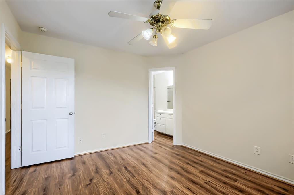 Room featuring wood-finish flooring, a ceiling fan with integrated lighting, and a six-panel door