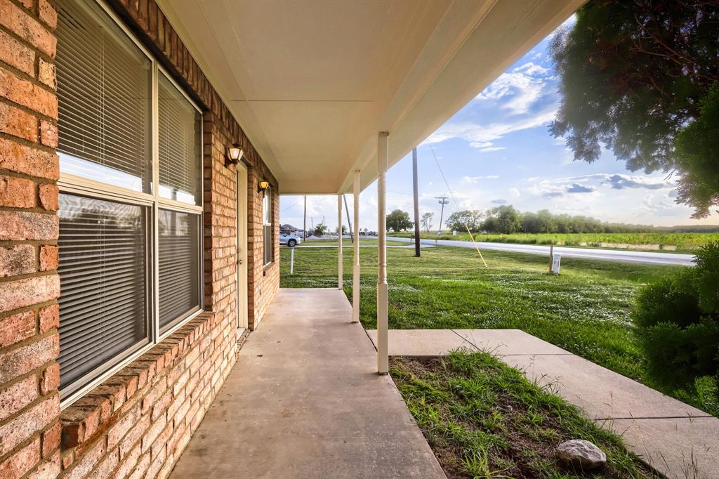 Covered porch featuring brick exterior walls, concrete flooring, and support columns Covered porch featuring brick exterior walls, concrete flooring, and support columns