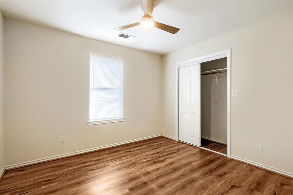 Interior space featuring wood-finish flooring, a neutral color palette, a ceiling fan with integrated lighting, and a closet with sliding doors