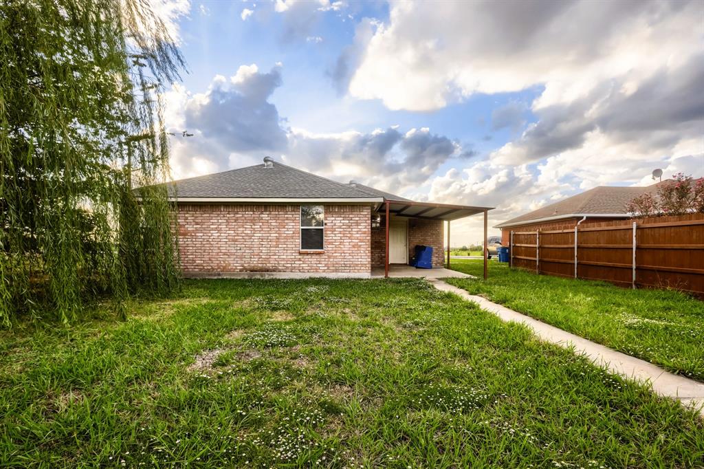 Brick exterior featuring a covered patio, concrete walkway, and wood privacy fencing