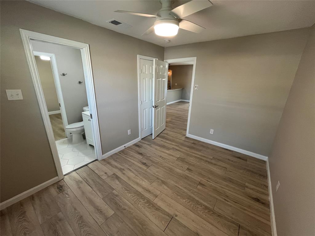 Wood-finish flooring, neutral wall tones, ceiling fan with integrated lighting, paneled interior doors, and hex-patterned tile flooring