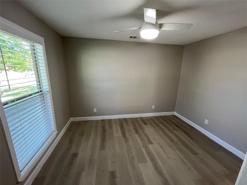 Interior room featuring wood-finish flooring, neutral wall paint, and a ceiling-mounted light fixture with a fan