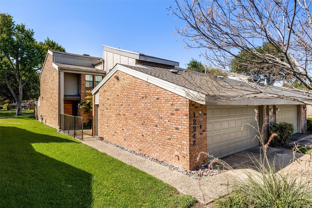 Multi-level exterior featuring a brick facade, low-pitch roofline, concrete driveway, and attached two-car garage