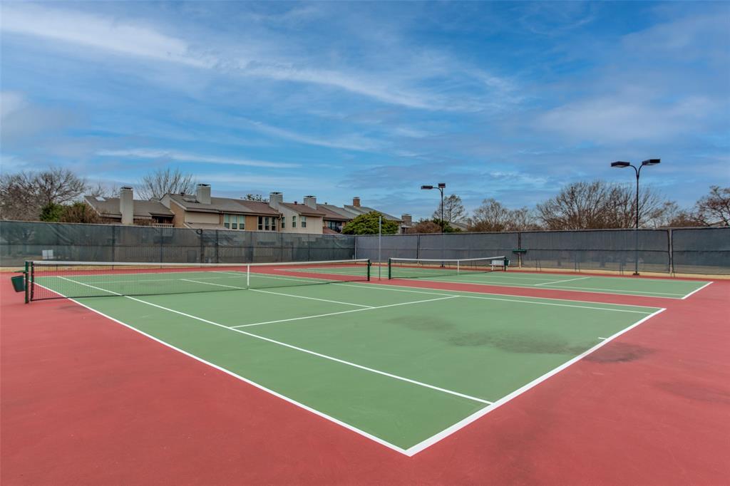 Dual hard-surface tennis courts featuring perimeter fencing and overhead court lighting