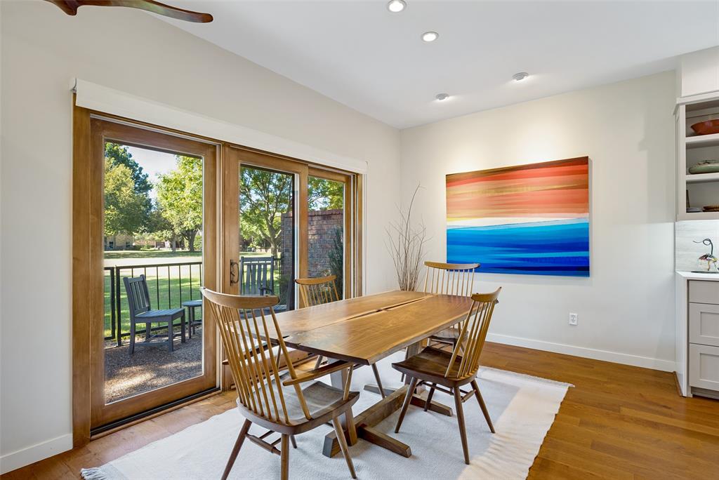 Wood-finish flooring, recessed lighting, and wooden-framed sliding glass doors opening to a hardscaped patio, complemented by built-in cabinetry