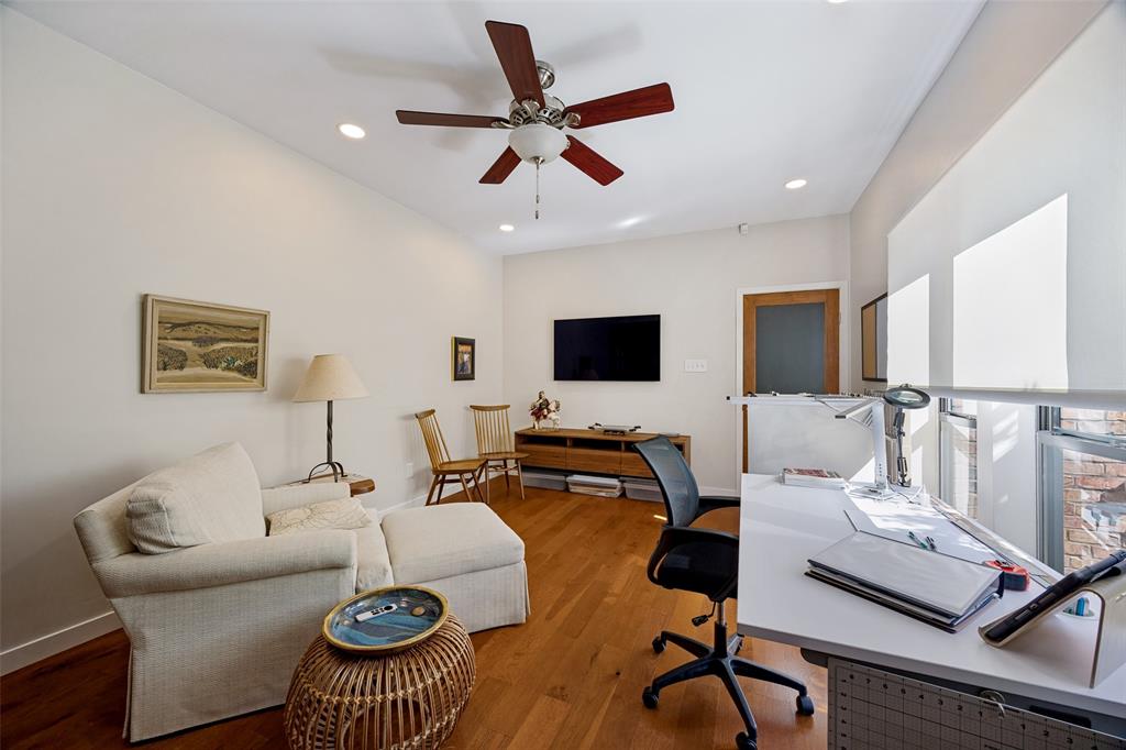 Room featuring wood-finish flooring, recessed lighting, ceiling fan, and large windows with roller shades