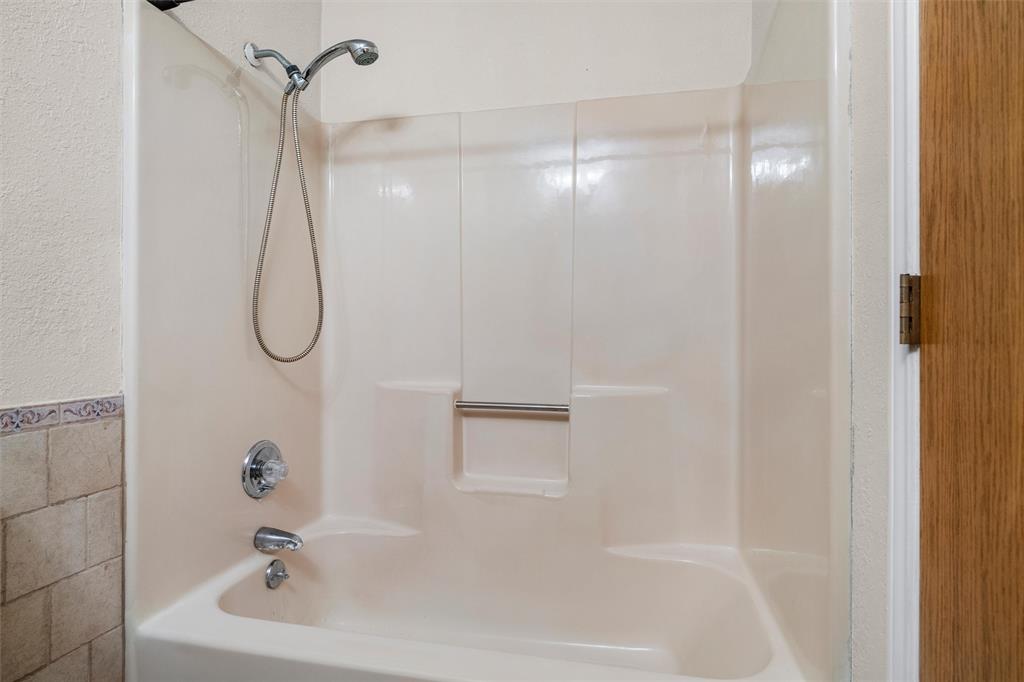 Tub-shower combination featuring a molded surround, integrated soap niche, handheld showerhead, and chrome-finished plumbing fixtures
