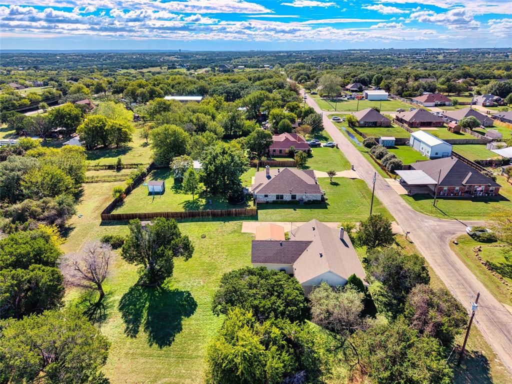 Aerial perspective of a sprawling property featuring expansive acreage, mature tree canopy, multi-level wood fencing, and a multi-pitched composition shingle roof